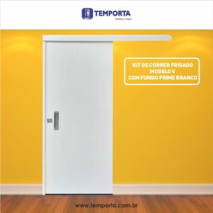 Porta de correr frisada modelo V na cor branca, com trilho superior embutido e puxador metálico, instalada em ambiente interno com parede amarela e piso de madeira. Texto na imagem destaca: “Kit de correr frisado modelo V com fundo prime branco” e a marca Temporta.