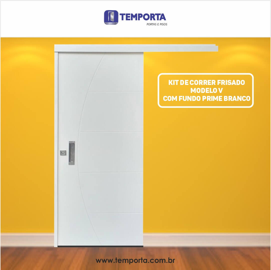 Porta de correr frisada modelo V na cor branca, com trilho superior embutido e puxador metálico, instalada em ambiente interno com parede amarela e piso de madeira. Texto na imagem destaca: “Kit de correr frisado modelo V com fundo prime branco” e a marca Temporta.