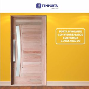 Porta pivotante de madeira sob medida com acabamento natural, visor em vidro no formato de arco, puxador metálico vertical e batente em madeira. Modelo moderno nas dimensões de 2,70 x 1,40 m com 20 cm de espessura, ideal para entrada principal de residências de alto padrão.